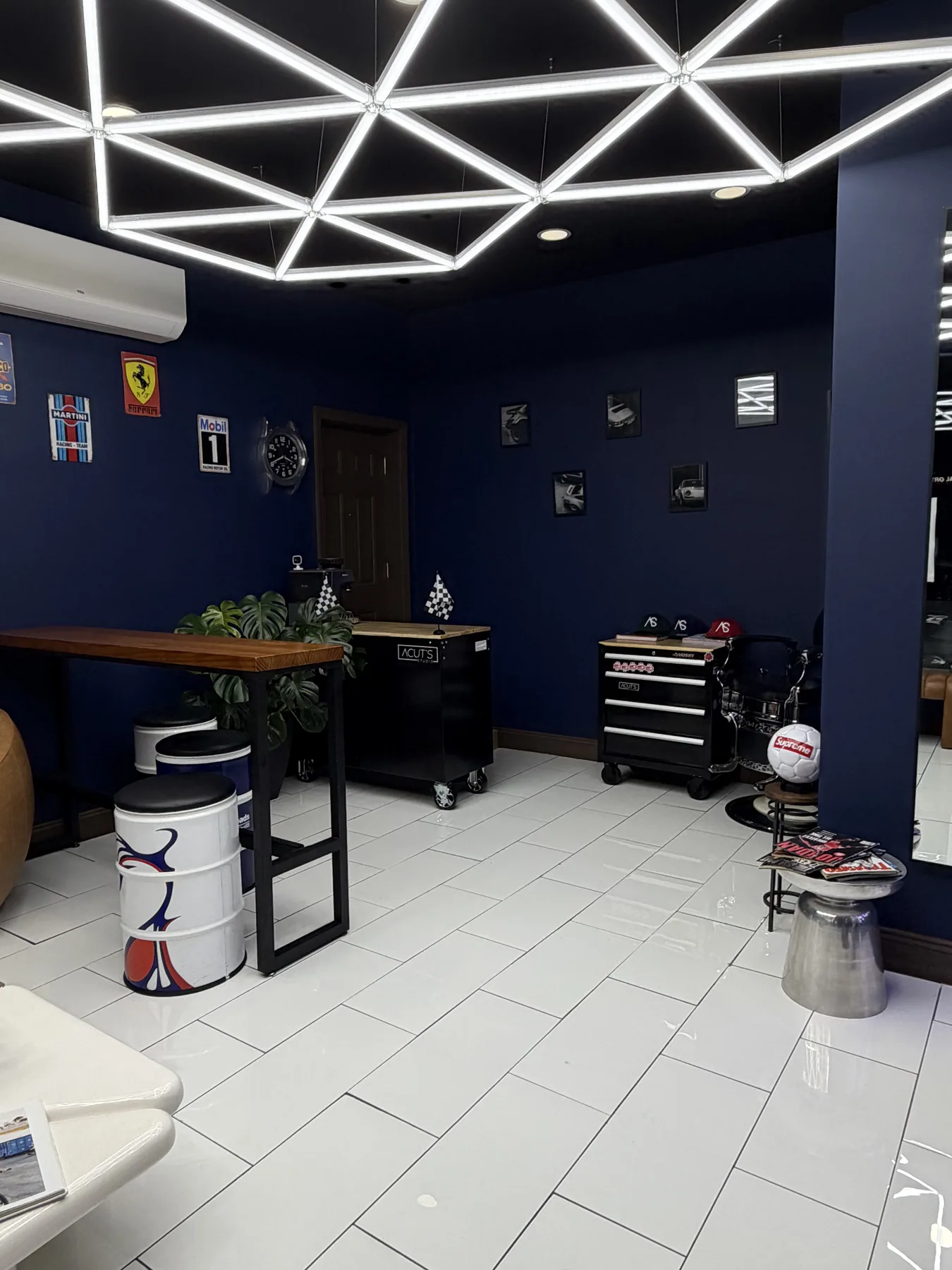 A Cuts Studio interior showing seating, barber stations, and geometric ceiling lighting